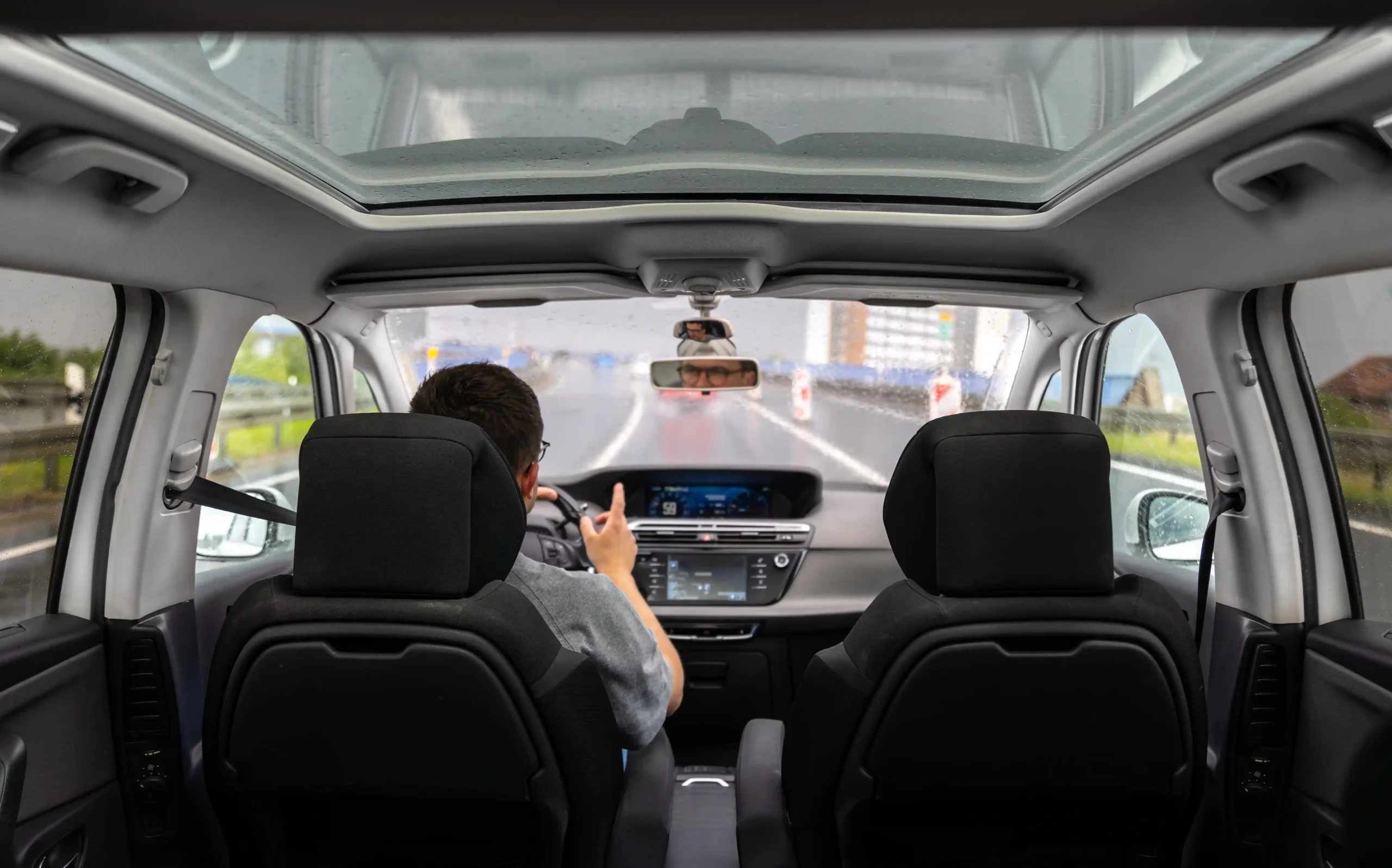 driving-rain-panoramic-roof-urban-road-with-traffic-signs